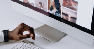 Man working on computer in modern office, viewing photography website. Clean and tech-focused environment.